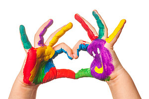 Zwei Hände mit bunten Fingermalfarben, die zusammen ein Herz formen