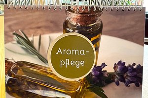 Aroma-Pflege: Bild eines Notizbuchs mit ätherischen Ölen und Lavendelblüten.