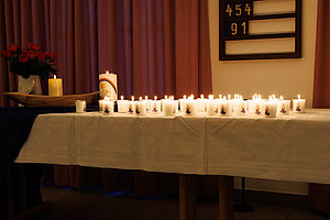 Dekorative Kerzen auf einem Tisch mit Blumenarrangement und sanftem Hintergrundlicht.