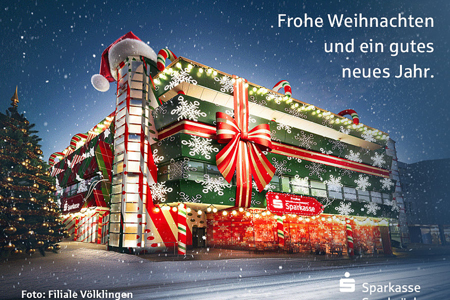 Weihnachtlich geschmücktes Sparkassen-Gebäude mit großen Geschenkband- und Schneeflockendekorationen, Schnee fällt, Text 'Frohe Weihnachten und ein gutes neues Jahr.'