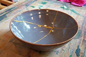 Schale mit goldenen Reparaturlinien auf bemaltem Holztisch