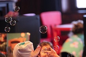 Kinder sitzen an einem Tisch und versuchen, Seifenblasen zu fangen