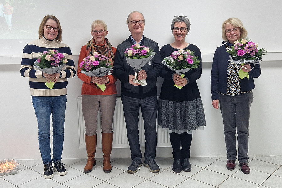Fünf Personen stehen nebeneinander, jede hält einen Blumenstrauß mit rosa und weißen Blüten.