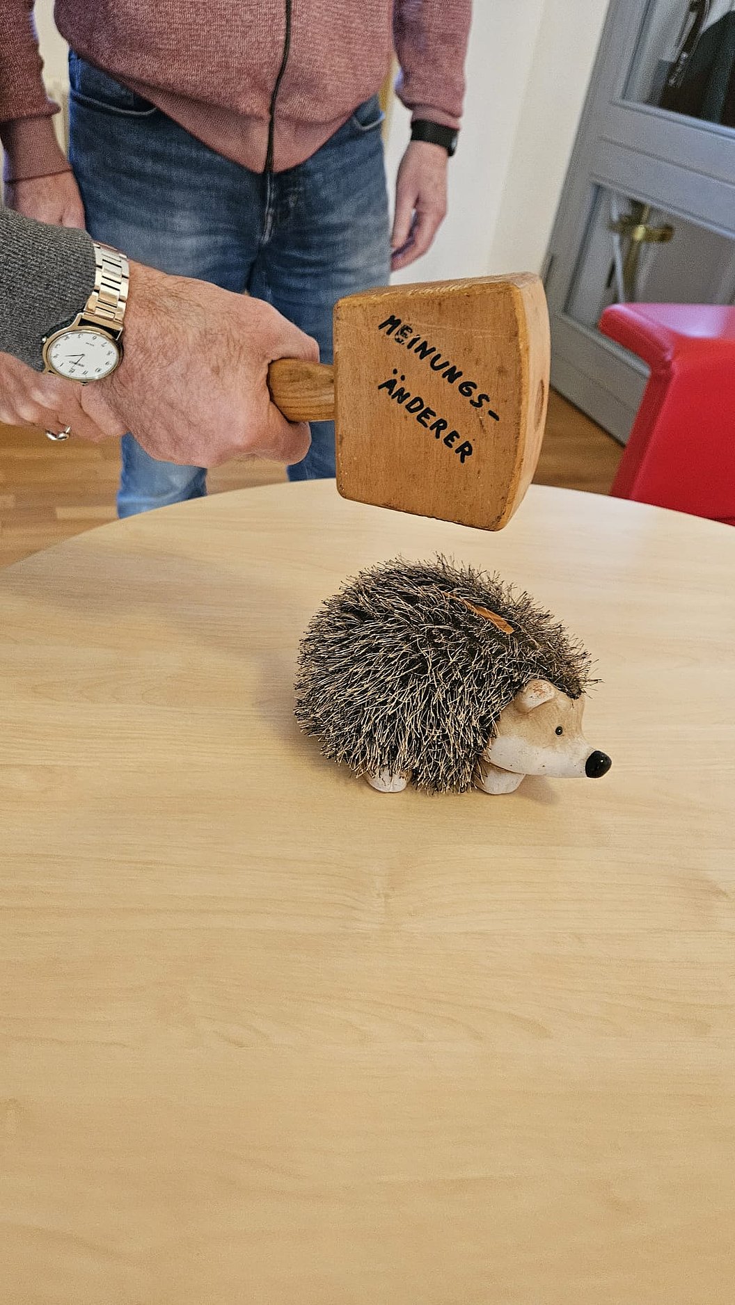 Niedlicher Igel und Holzhammer mit der Aufschrift 'Meinungsänderer' auf einem Tisch.