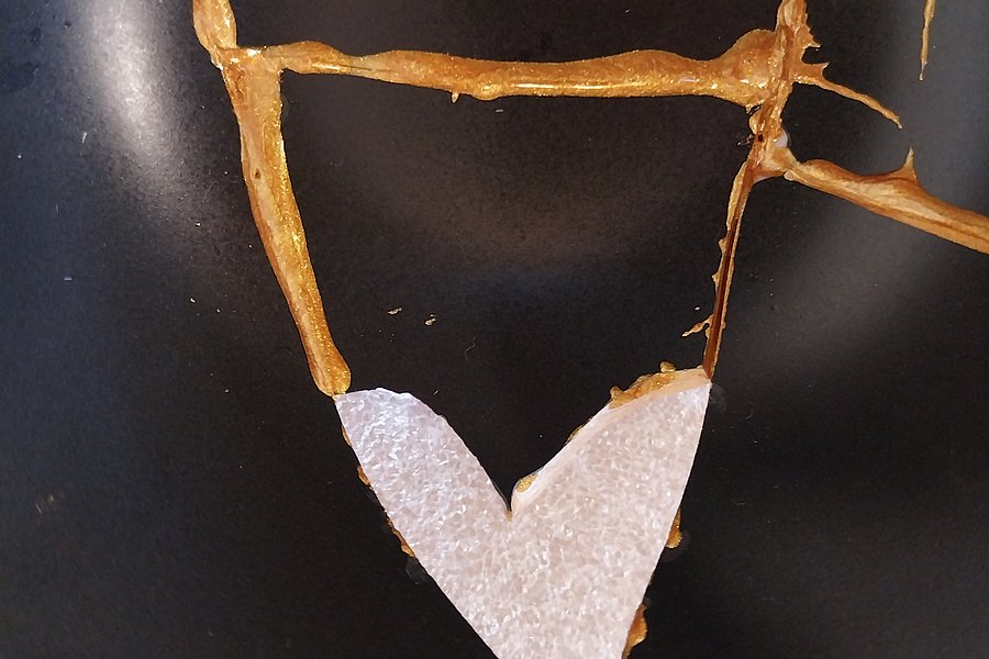 Schwarze Keramik mit goldener Kintsugi-Reparatur und einer herzförmigen Bruchstelle