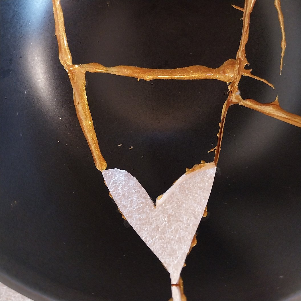 Schwarze Keramik mit goldener Kintsugi-Reparatur und einer herzförmigen Bruchstelle