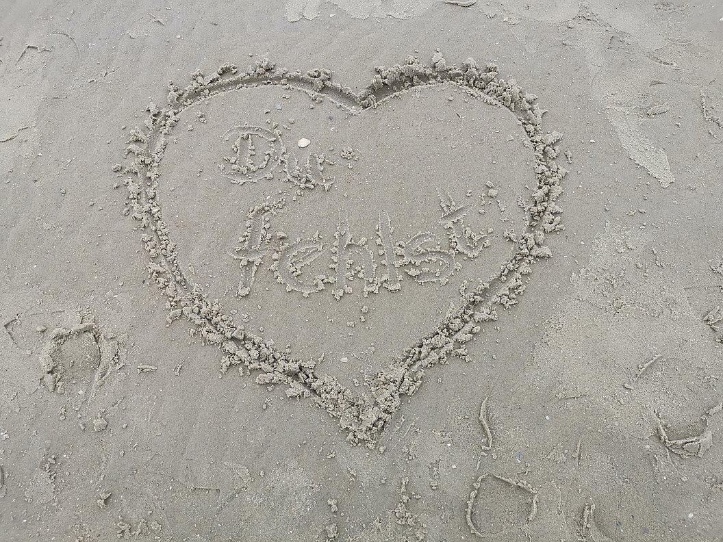 Herz in den Sand gezeichnet mit der Aufschrift 'Du fehlst'