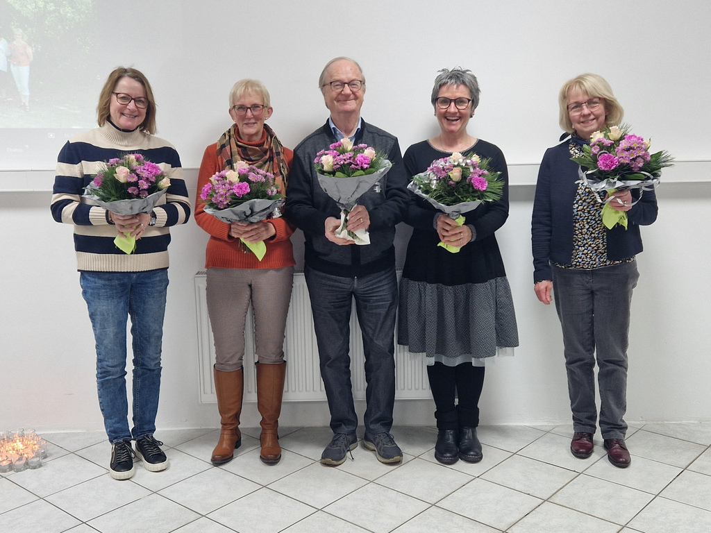 Fünf Personen stehen nebeneinander, jede hält einen Blumenstrauß mit rosa und weißen Blüten.